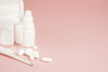 White medical pills and medical preparations in with bottles, glass ampoues, pink background. Closeup photo of medical preparations with copy spaes.