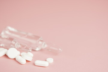 White medical pills and medical preparations in with bottles, glass ampoues, pink background....