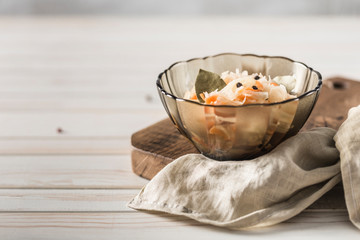Fermented cabbage in a transparent plate on a wooden Board with a linen napkin on a light background.
