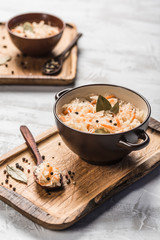Fermented cabbage in a plate on a wooden tray with a spoon on a light background.