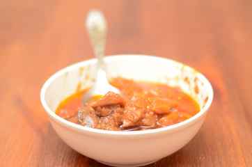 Homemade food.Zucchini and tomato lecho in bowl on wooden table.Minimalist style.