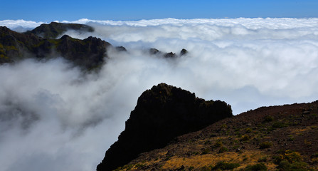 Pico do Areeiro Madeira peaks  among clouds with blue sky above.