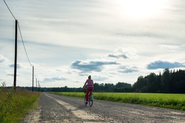 Woman cycling on a countryside road in summer. Photo taken in Lokuta, Turi, in Jarva County, Estonia
