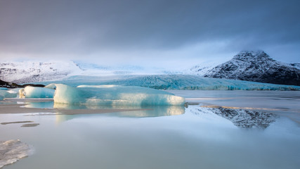 Iceland winter: iceberg and mountains reflected in a lake