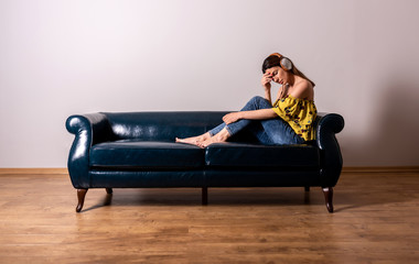 Obraz premium A serious woman listening to music on a sofa