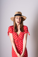 A concerned woman in a red dress standing in a studio