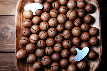 Macadamia in a bamboo bowl. Useful nuts. The key for nuts and healthy food. Nut wrench.