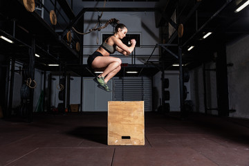 Young strong sweaty fit muscular girl with big muscles doing box jump hardcore crossfit workout...