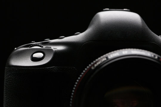 Professional modern DSLR camera low key stock photo/image - Modern DSLR camera with a very wide aperture lens on with highlighted edges against black background