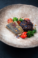 Gebratenes Gourmet Fisch Filet vom Skrei Kabeljau mit Kalette und schwarzen Venus Reis als closeup...