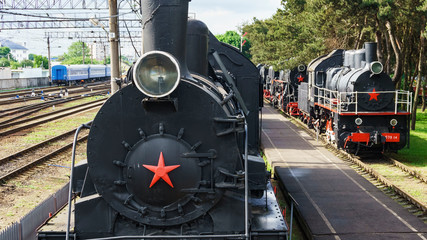View of old classic black steam locomotives with red decoration on railroad track.