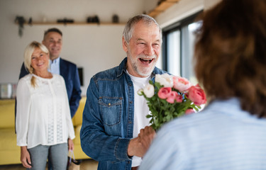 Group of senior friends at dinner party at home, greeting.