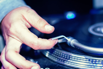 DJ turnablist positioning needle on vinyl record closeup