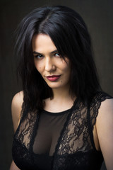 Portrait of a young sexy brunette girl in a lace top in dramatic tones. Vintage photo.