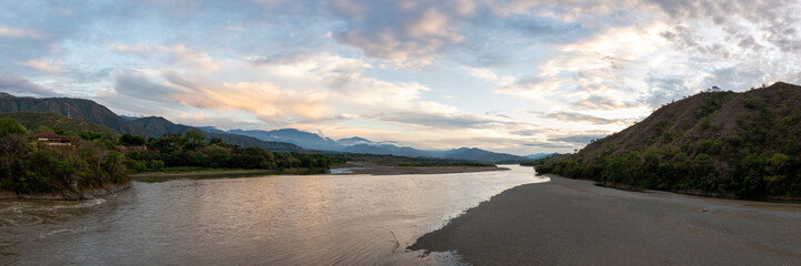 Fototapeta na wymiar Panoramic View of the Cauca River Between the Santa Fe City of and Olaya City, Surrounded by Mountains and Lots of Vegetation