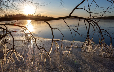 Spring time scenery on the lake shore. Melted ice on the beach. Wintry landscape in Finland. Sunny day and melting ice on branches.
