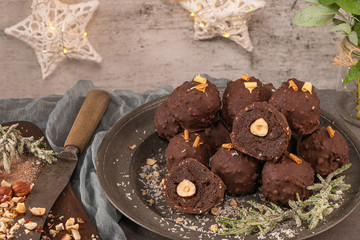 Dark chocolate truffles with hazelnuts on plate.