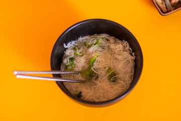 Bowl of delicious Japanese noddles in a yellow background