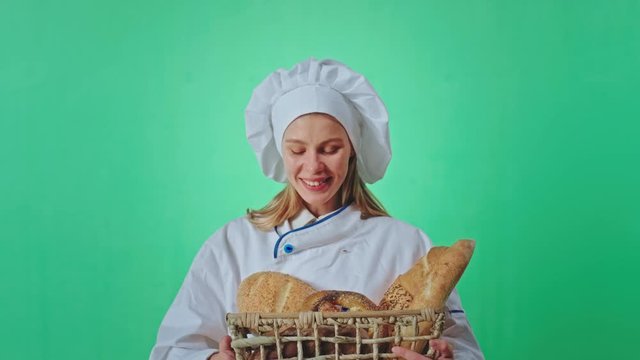 Good looking woman baker with a large smile holding a basket of a fresh bread she gesticulating with hands to let the smell to go in front of the camera