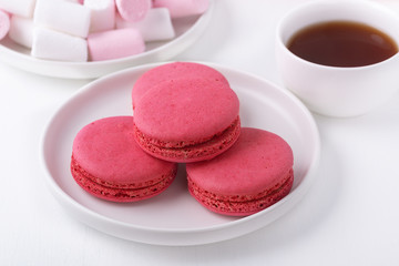  Macaroons, marshmallows and coffee on a white wooden table.