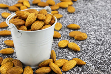 Almonds in a white bucket and on black and white marble