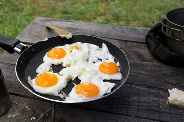 Fried eggs cooked in frying pan on camping gas stove