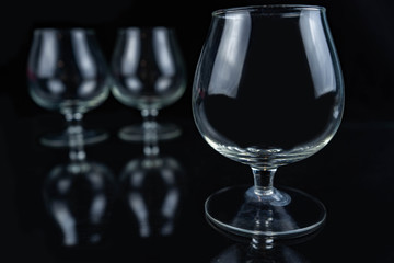 Three empty whiskey / cognac glasses on a black dark background