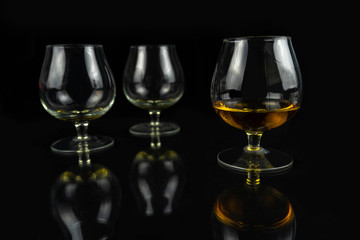Three whiskey / cognac glasses on a black dark background