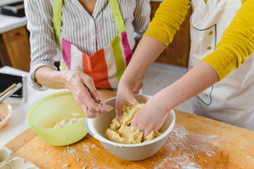 Grandmother and her granddaughter making cakes together in the home kitchen. Children helping adults.