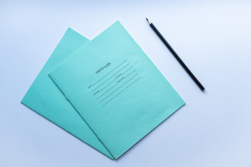 Top view of two pupils copybooks with black pencil on white background. Concept of education, minimalism.