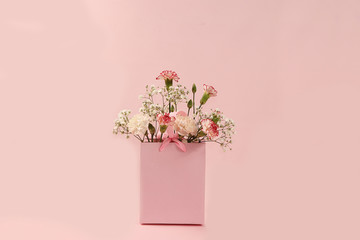 Carnations in a pink box, abstract spring floral background. Creative modern bouquet, minimal holiday concept. Greeting card for Women's Day or Mother's Day, happy birthday, wedding, 