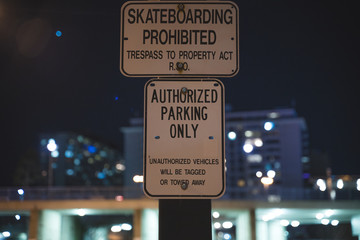 Skateboarding Prohibited and Authorized Parking Only Signs in Dark Background At Night