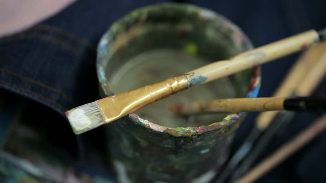Artists brushes and oil paints on glass with water closeup