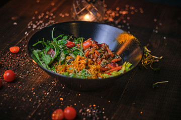 Delicious, vegetarian plate of meal which includes cooked vegetarian pilaf served with healthy mix of ruccola leafs, bulgarian pepper, thin sliced vegetables, cherry tomatoes and spices, on a black