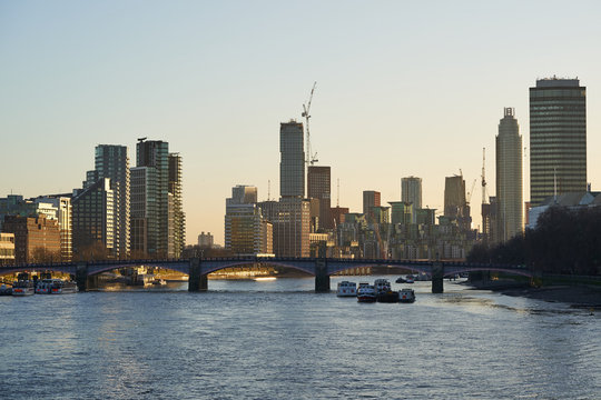 Cityscape or panoramatic Picture of London, capitol of Great Britain, taken in sunny sunset during the golden hour shown bridge over the river Thames and modern architecture with skyscrapers.