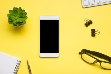 Yellow desk office with laptop, smartphone and other work supplies with cup of coffee. Top view...