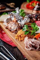 Turkish cuisine. Lamb kebab with bulgur porridge, grilled vegetables on pita bread. Serving dishes in a restaurant on a wooden board. background image, copy space text