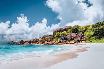 Fototapeta na wymiar Grand Anse tropical beach in La Digue, Seychelles. Famous granite rock formations and white clouds above