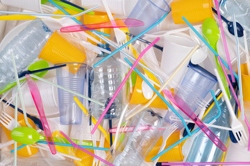 Disposable single use plastic objects such as bottles, cups, forks, spoons and drinking straws that cause pollution of the environment, especially oceans. Top view.