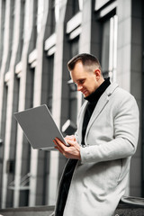 Stylish guy on the street looks at the laptop 