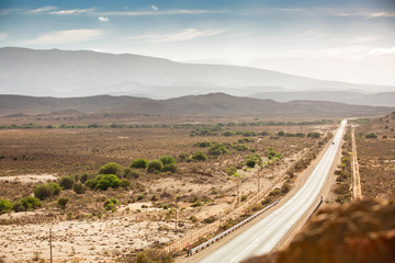 Scenic road through South African landscape with meadow mountains in the background along route 62