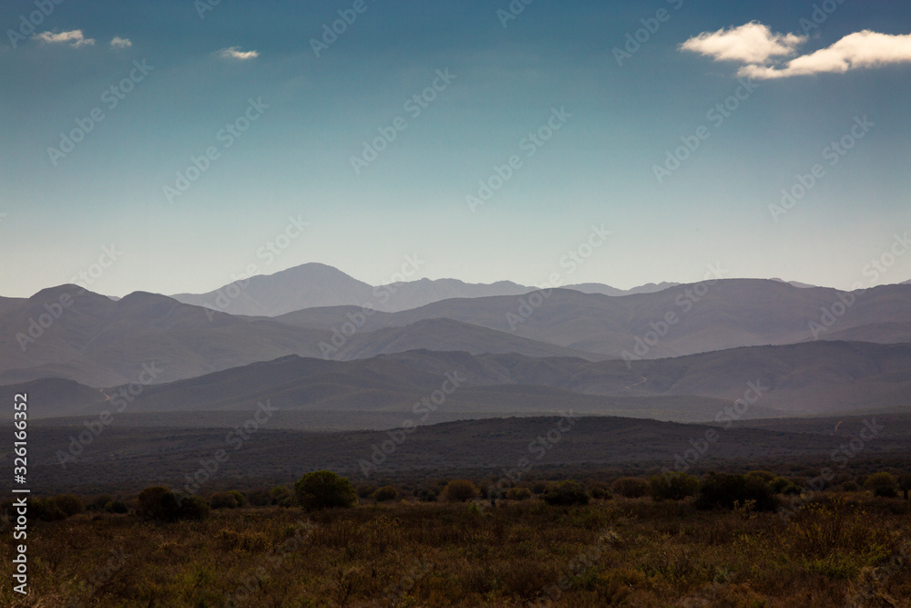 Wall mural Meadow hills ridges and mountain background with blue sky and clouds