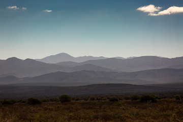 Meadow hills ridges and mountain background with blue sky and clouds