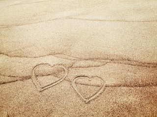 Two hearts painted on wet sand. Love concept. 