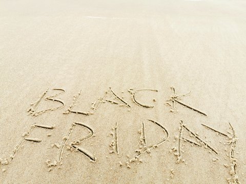 Black Friday poster. Embossing on wet sand. Summer beach background. 