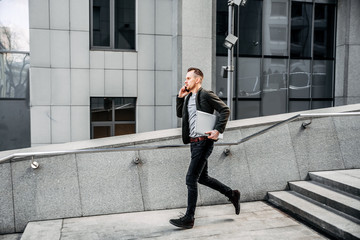 man with a laptop runs up the stairs to the office