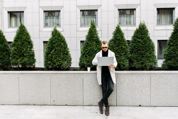 A guy in a smart casual with a laptop outdoor