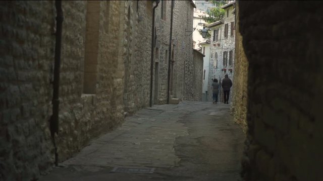 Two People Walking in a Shady Alley