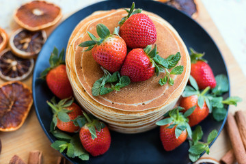 Brunch, favorite morning meal. Homemade berry  pancakes, fresh summer dessert with strawberries on wooden table, close up, selective focus.
