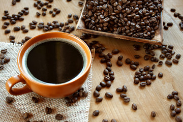 Czarna kawa w brązowej filiżance na tle ziaren kawy - obrazy, fototapety, plakaty